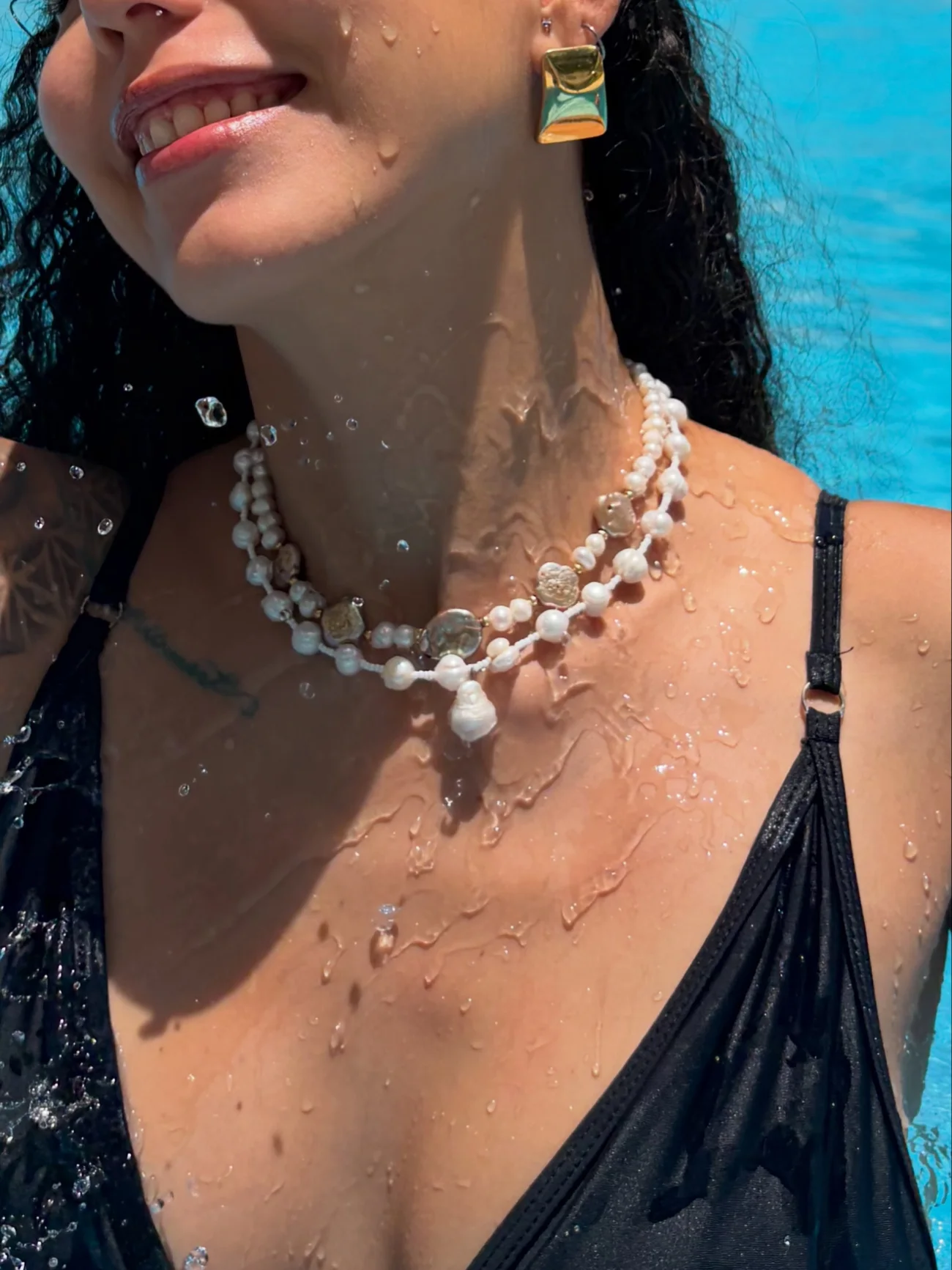 Mujer flotando en una alberca con un collar de perlas de río.
